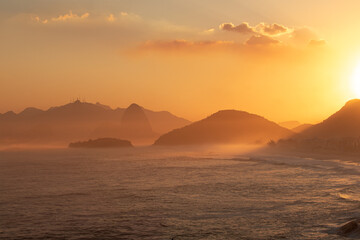 a view of a sunset with mountains in the distance and ocean