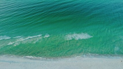 Aerial flight along a pristine white sand beach with beautiful emerald green ocean waves