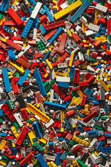 Fototapeta premium A chaotic yet colorful jumble of toy bricks, tightly packed to fill the entire frame. The bricks come in various sizes and an array of colors including red, blue, green, yellow, and white,