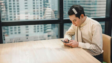 Portrait of cute beautiful young man hold in hand use mobile cell phone working in a model office. Transgender people and Equality concept.