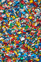 Fototapeta premium A chaotic yet colorful jumble of toy bricks, tightly packed to fill the entire frame. The bricks come in various sizes and an array of colors including red, blue, green, yellow, and white,