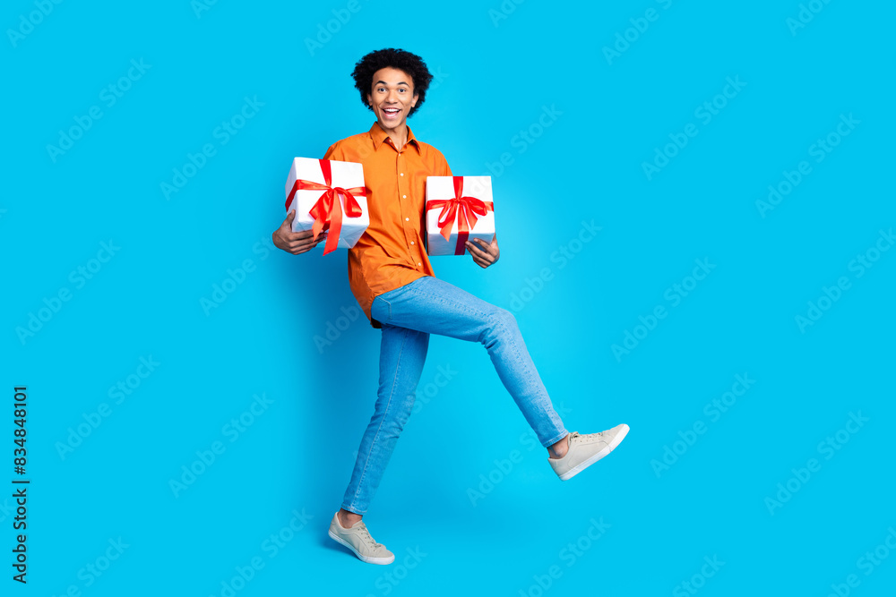 Poster full length photo of handsome good mood guy wear orange shirt rising gift box emtpy space isolated b