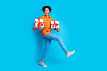 Full length photo of handsome good mood guy wear orange shirt rising gift box emtpy space isolated blue color background