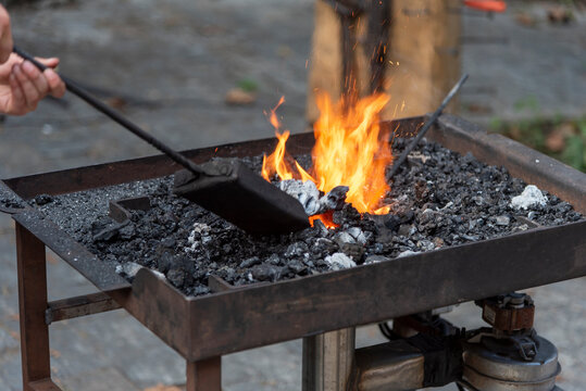Detail shot of a blacksmith's ember while working with a flame and charcoal.