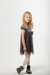 A little blonde girl in a dress and black boots poses