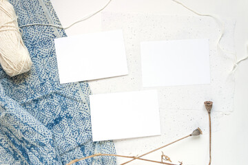 Top view of a table with three blank white cards decorated with hand-dyed fabric