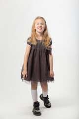 A little blonde girl in a dress and black boots poses
