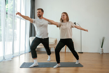 Warrior asana. Man and woman are doing yoga exercises at home