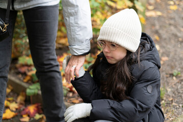 Little beautiful sad girl in glasses and a hat cries in late autumn in the park