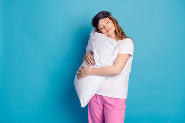 Photo of charming lovely cute girl wear white trendy pajama lying soft pillow isolated on blue...