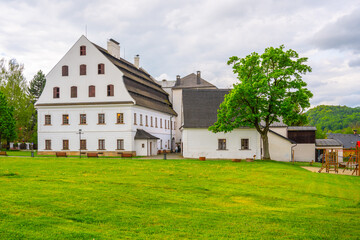 A view of the historic paper mill building in Velke Losiny, Czechia. The building is white with a distinctive roof, showcasing its traditional design.