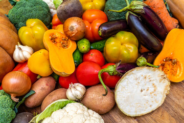 Various vegetables are laid out on a wooden table. Large assortment of vegetables food. pumpkin cabbage broccoli pepper tomatoes carrots and others
