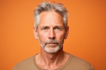 Obraz premium Photo of a man, aged 45 and older, with a flirtatious gaze on a light orange background