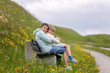 Children, boy brothers in Switzerlands Alps on a spring day with pet maltese dog, traveling.