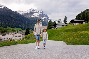 Children, boy brothers in Switzerlands Alps on a spring day with pet maltese dog, traveling.