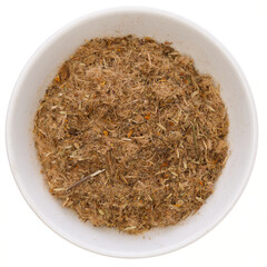 Overhead view of dried arnica flowers (Arnica montana) in a white bowl, isolated on white background