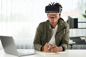 Young African American studying through VR glasses online course meeting hologram looking metaverse...