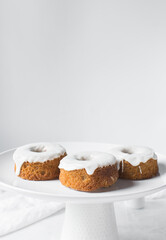 Iced mini bundt cake on a white plate, vanilla bundlette with on a plate, small vanilla bundt cake with an icing glaze
