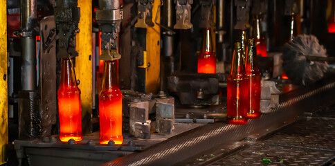 Glass factory, production of glass containers. Molten glass is blown into molds. Robotics in industry. Modern technologies, robotic machines produce products. Technological work at the plant.