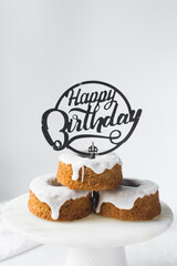Happy birthday sign on a stack of iced mini bundt cakes, individual birthday cakes, bundtlettes stacked with a happy birthday cake topper