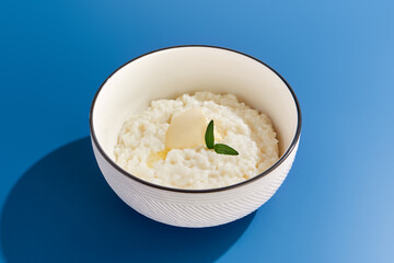 Nutrient-Rich Rice Porridge in White Bowl on Blue Background**