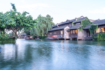 Obraz premium Discover China Wuzhen's ancient architecture, where old stone paths and bridges reflect on peaceful waters. Experience the charm of historic buildings along serene rivers..