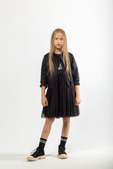 A full-length portrait of a young girl with long brown hair dressed in a hooligan style.