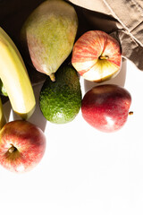 Fruits lie on a white table. Food shopping. Apples, bananas, avocado and mango close-up. Copy space. Top view