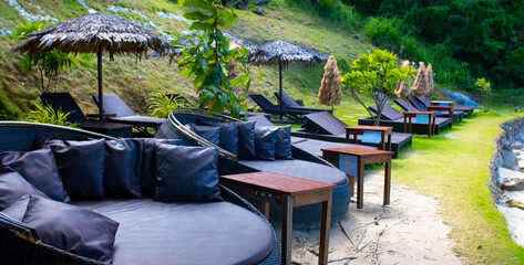 Round sun loungers on the beach area of the hotel by the sea. Sun loungers by the pool with tables and umbrellas.