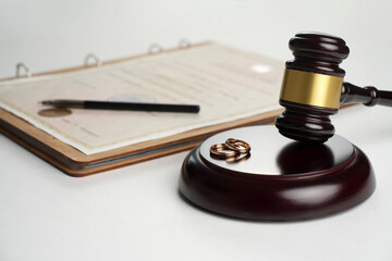 Marriage contract, golden wedding rings and gavel on white background, close-up
