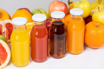 Different types of fruit juices - orange, grapefruit, apple and multifruit in glass bottles.