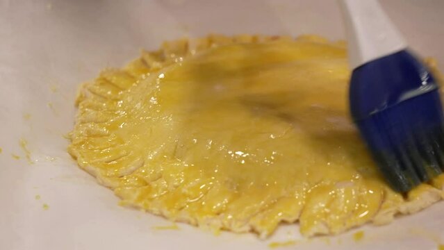 brushing of egg on the cake before being baked in the oven
