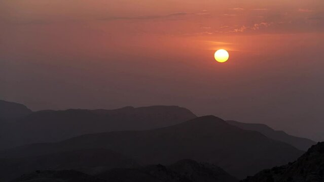 timelapse of the sun setting behind the mountains
