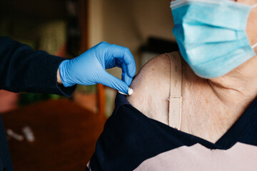 Close up of a healthcare worker, wearing blue gloves, preparing to administer a vaccine to an...