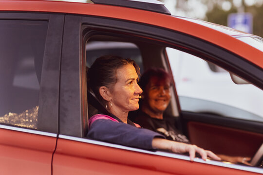 two middle aged women sitting in a car with the windows down