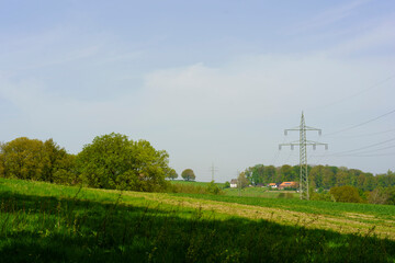 High-voltage power lines in a sunny meadow in spring