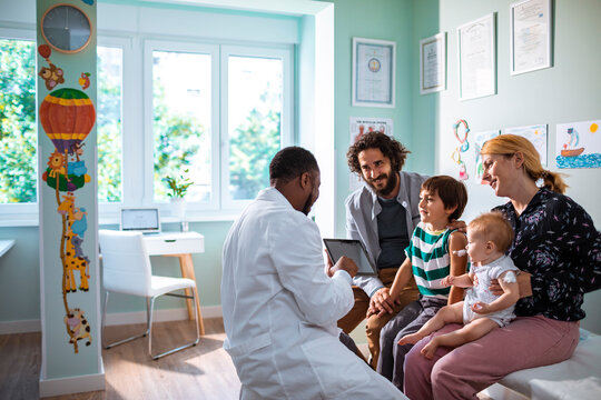 Family at pediatrician's office for children's check-up with doctor