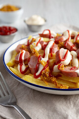 Homemade Salchipapa Fries with Ketchup, Mustard and Mayo on a Plate, low angle view. Close-up.