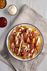 Homemade Salchipapa Fries with Ketchup, Mustard and Mayo on a Plate, top view.