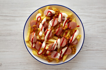 Homemade Salchipapa Fries with Ketchup, Mustard and Mayo on a Plate, top view.
