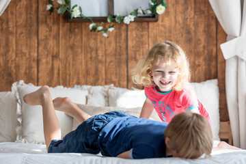 Cute sweet toddler children, tickling feet on the bed, laughing and smiling