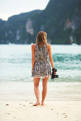 Woman, back and camera on beach in Maldives for vacation, holiday and photography on island. Female photographer, ocean and shoreline in nature for travel, tourism and trip to paradise for memories