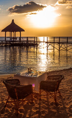 Coucher de soleil sur plage mauricienne et table préparée pour un dîner romantique 
