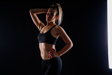 Obraz premium Fit sportswoman in leggings and sports bra looking away and while standing on yellow red