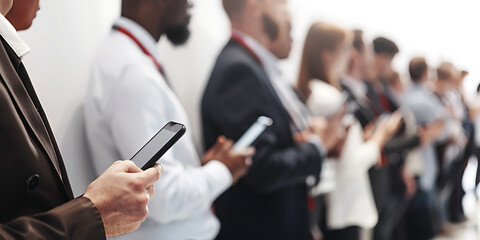 Business People distracted by Smartphones at Event - hands holding mobile devices. 