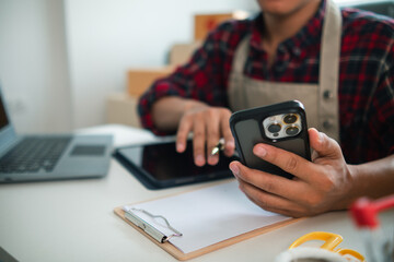 businessman decides invest in small SME business at home by using laptop and smartphone do online marketing and sell things online through an application before packing products according to orders.