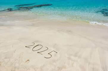 The year 2025 written in the sand at the beach