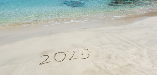 The year 2025 written in the sand at the beach