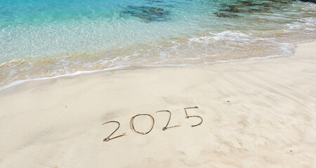 The year 2025 written in the sand at the beach