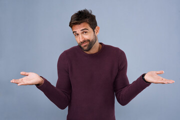 Smile, portrait and man in studio, question and confused with hands, why and asking with gesture. Blue background, mockup and fashion for person with cardigan, shrug and offer for sale of clothes